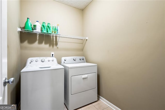 laundry area with light tile patterned floors, a textured ceiling, and separate washer and dryer