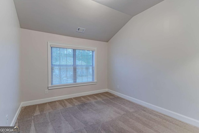 unfurnished room with light carpet and vaulted ceiling