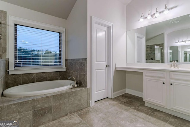 bathroom with vanity, lofted ceiling, and tiled tub