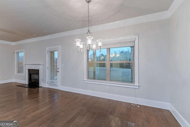 unfurnished living room featuring hardwood / wood-style floors, an inviting chandelier, a wealth of natural light, and crown molding