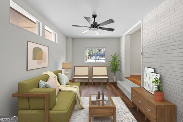 living room featuring dark hardwood / wood-style floors, ceiling fan, and brick wall