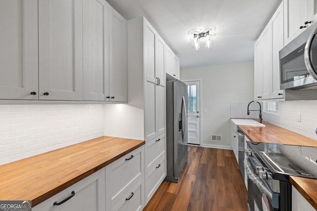 kitchen featuring wooden counters, appliances with stainless steel finishes, dark hardwood / wood-style flooring, and white cabinets