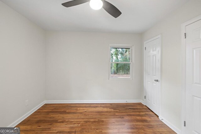 empty room with ceiling fan and dark wood-type flooring