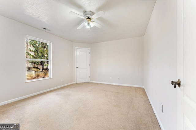 carpeted spare room featuring ceiling fan and a textured ceiling