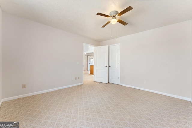 spare room featuring light carpet, ceiling fan, and a textured ceiling