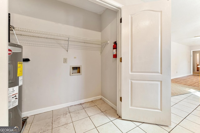 laundry room with water heater, light tile patterned flooring, and washer hookup