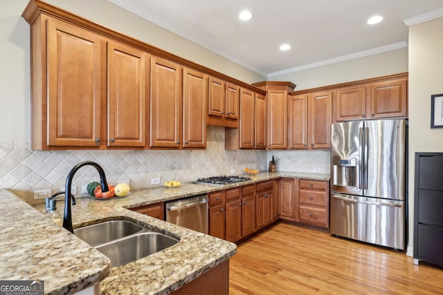 kitchen featuring light stone countertops, appliances with stainless steel finishes, light hardwood / wood-style flooring, and ornamental molding