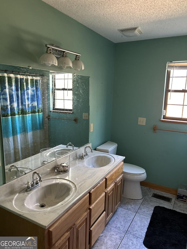 bathroom featuring tile patterned flooring, vanity, a textured ceiling, and toilet