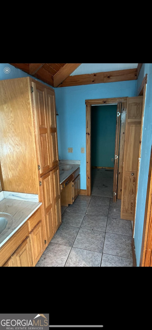 bathroom featuring beam ceiling, tile patterned flooring, and sink