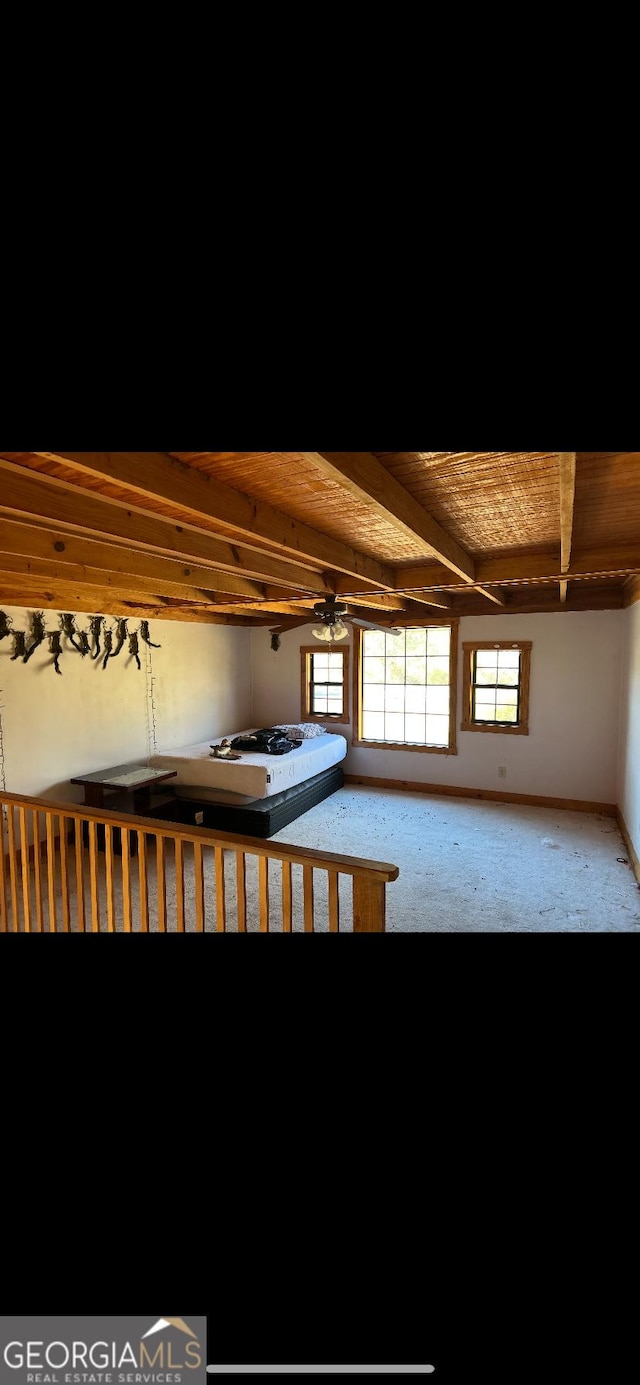 interior space with beam ceiling, ceiling fan, carpet flooring, and wood ceiling