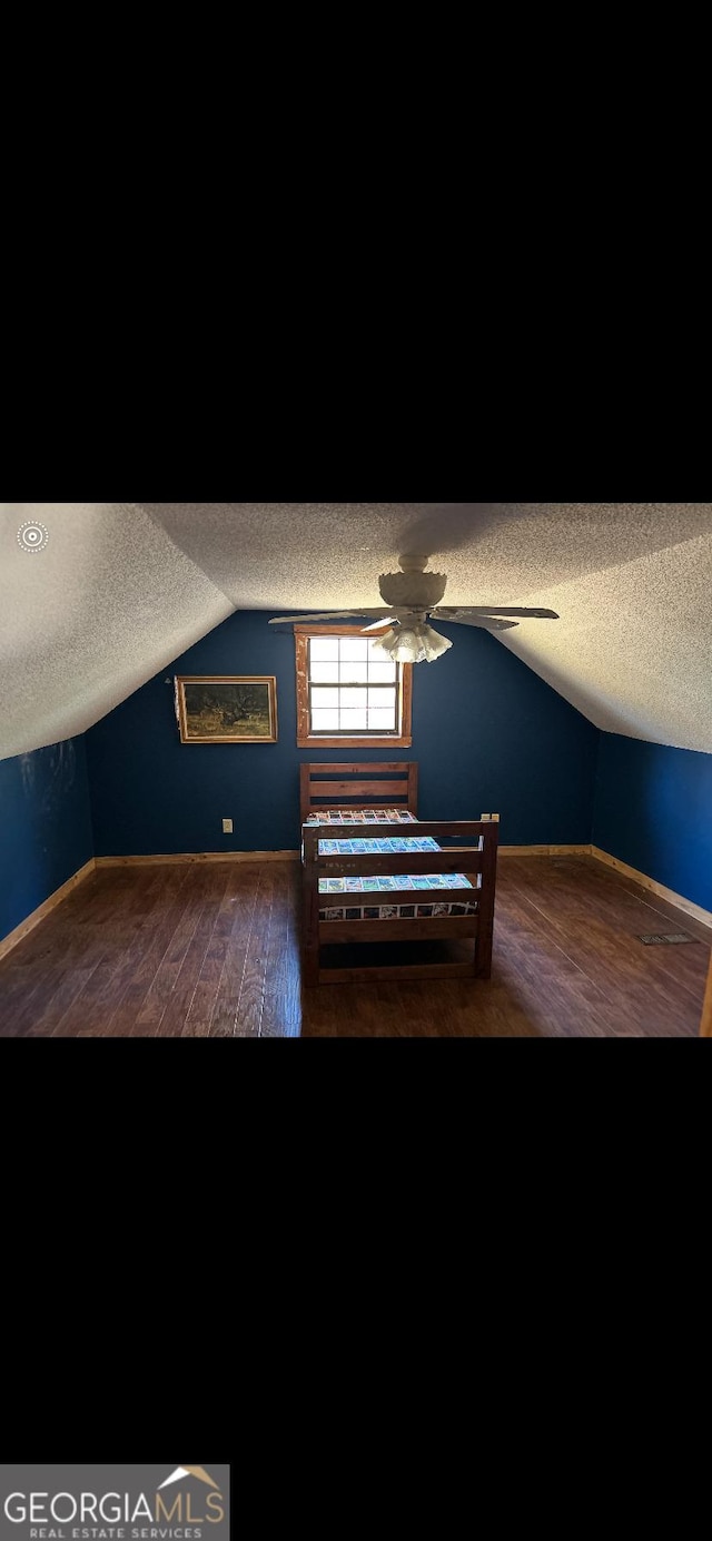 additional living space featuring a textured ceiling, lofted ceiling, ceiling fan, and dark hardwood / wood-style floors