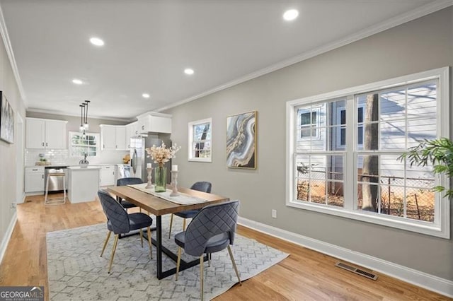 dining area with crown molding and light wood-type flooring