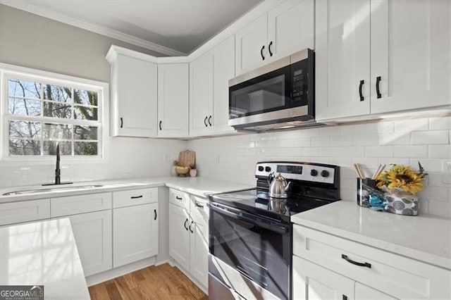 kitchen with crown molding, sink, white cabinets, and appliances with stainless steel finishes