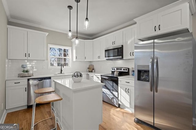 kitchen with a kitchen breakfast bar, stainless steel appliances, a kitchen island, white cabinetry, and hanging light fixtures