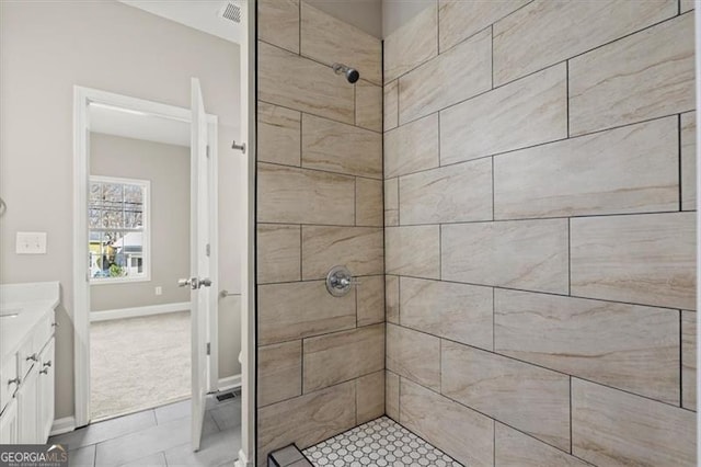 bathroom featuring tiled shower, vanity, and tile patterned floors