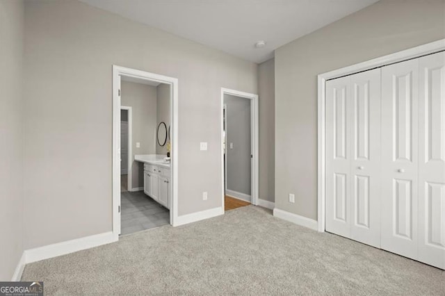 unfurnished bedroom featuring light carpet, connected bathroom, and a closet