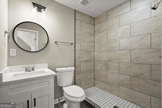 bathroom with tiled shower, vanity, and toilet