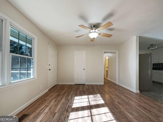 unfurnished bedroom with dark hardwood / wood-style floors, stainless steel fridge, ceiling fan, a textured ceiling, and connected bathroom