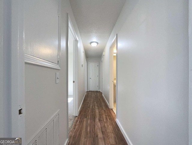 hallway featuring dark hardwood / wood-style flooring and a textured ceiling