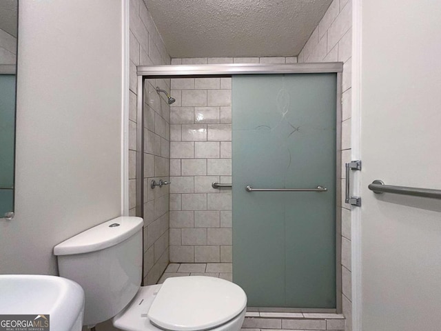 bathroom featuring toilet, a shower with shower door, and a textured ceiling