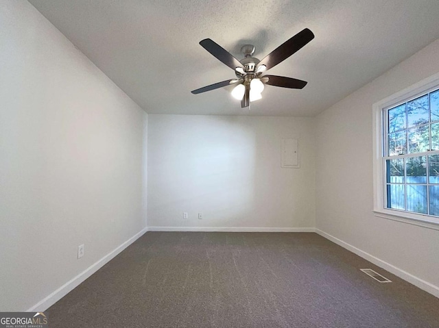 spare room with dark colored carpet, ceiling fan, and a textured ceiling