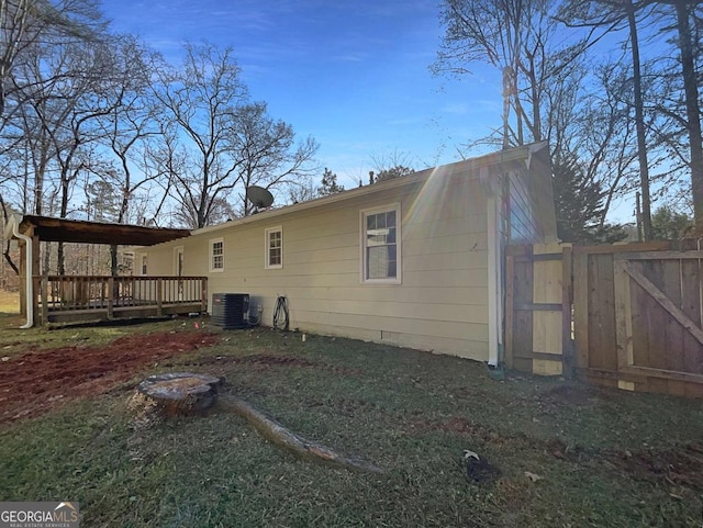 rear view of house with central AC unit and a wooden deck