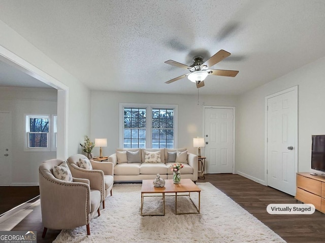 living room featuring a textured ceiling, ceiling fan, and dark wood-type flooring