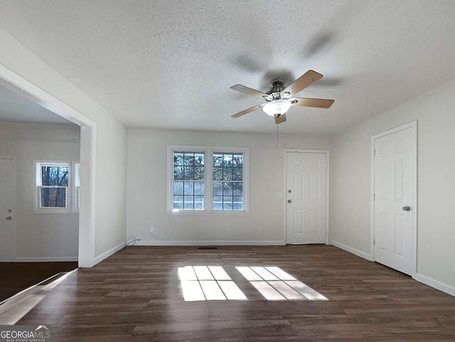 empty room featuring ceiling fan, dark wood-type flooring, and a textured ceiling