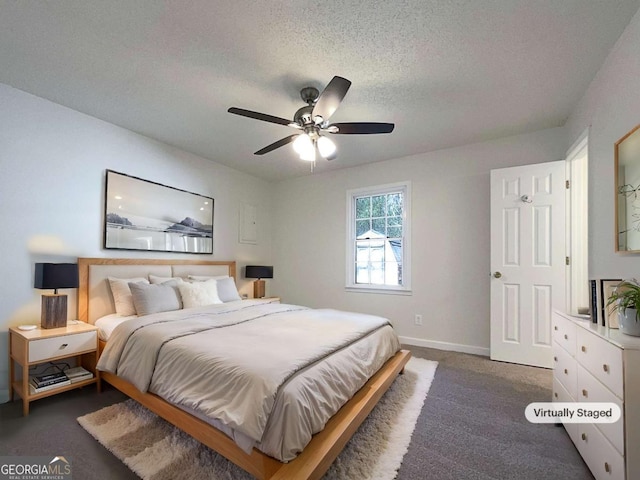 bedroom featuring a textured ceiling, dark carpet, and ceiling fan