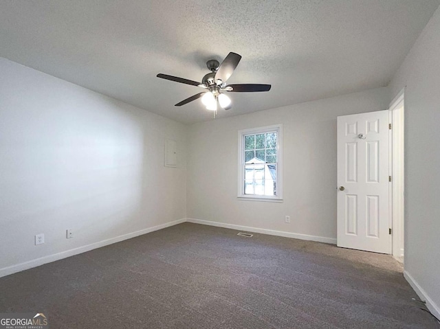 spare room with dark colored carpet, a textured ceiling, and ceiling fan