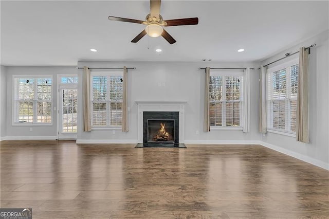 unfurnished living room featuring ceiling fan, plenty of natural light, and dark wood-type flooring