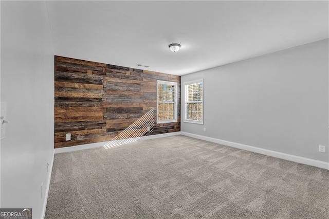 unfurnished room featuring wooden walls and carpet floors