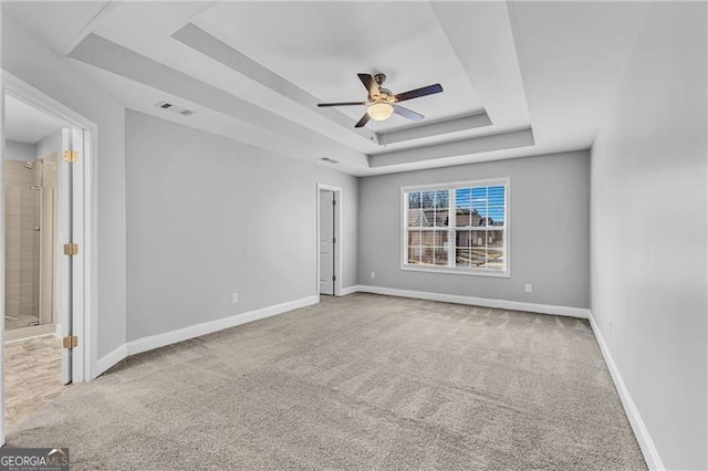 carpeted empty room featuring a tray ceiling and ceiling fan