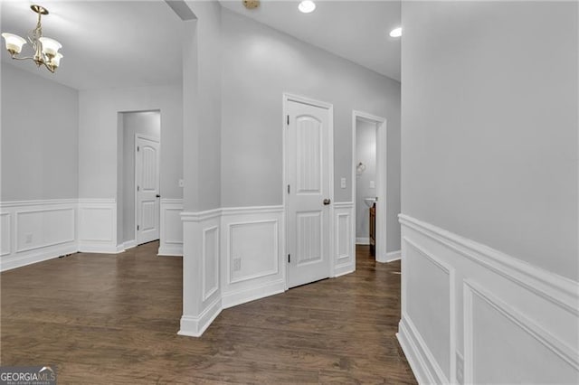 corridor with dark hardwood / wood-style flooring and a chandelier