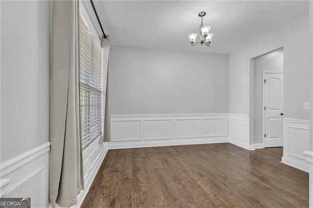 empty room featuring a chandelier and dark wood-type flooring