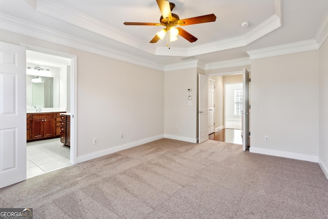 unfurnished bedroom with a raised ceiling, connected bathroom, crown molding, and light colored carpet