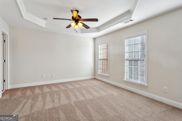 spare room with light colored carpet, a raised ceiling, ceiling fan, and ornamental molding