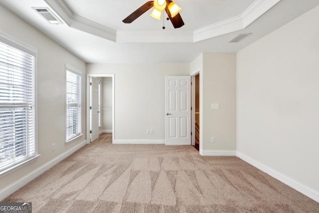 empty room featuring ceiling fan, a raised ceiling, crown molding, and light carpet