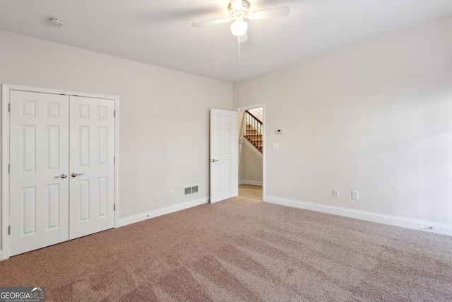 unfurnished bedroom with ceiling fan, light carpet, and a closet