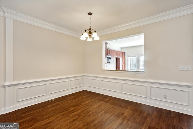 spare room featuring hardwood / wood-style floors, ornamental molding, and an inviting chandelier