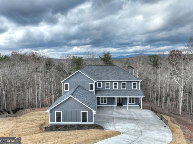 traditional-style house featuring board and batten siding, a front lawn, and a shingled roof