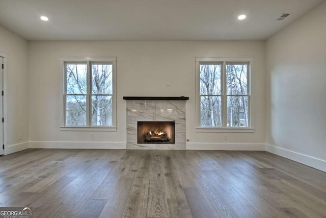 unfurnished living room with wood finished floors, a healthy amount of sunlight, and baseboards