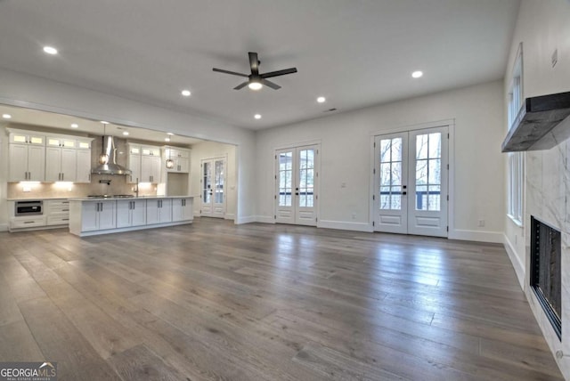 unfurnished living room with french doors, dark wood-style flooring, ceiling fan, and a fireplace