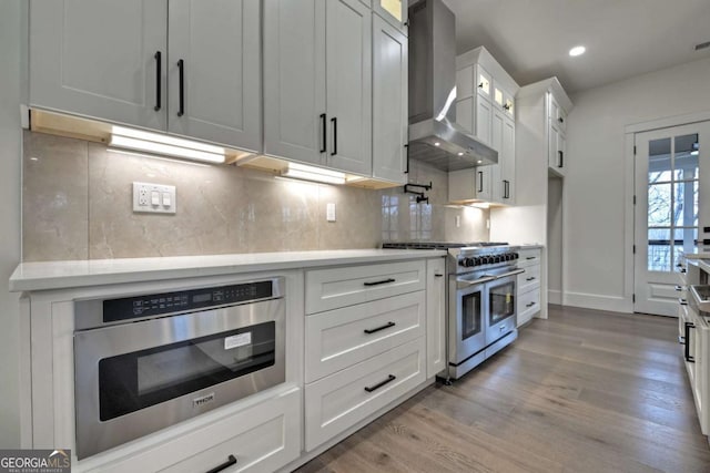 kitchen with range with two ovens, oven, wall chimney exhaust hood, and light countertops