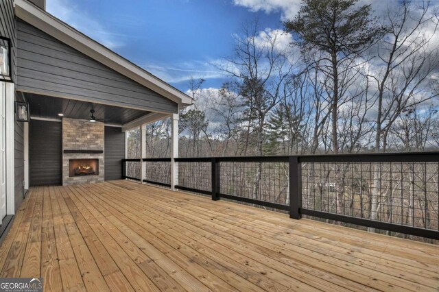 wooden deck featuring a large fireplace and a ceiling fan