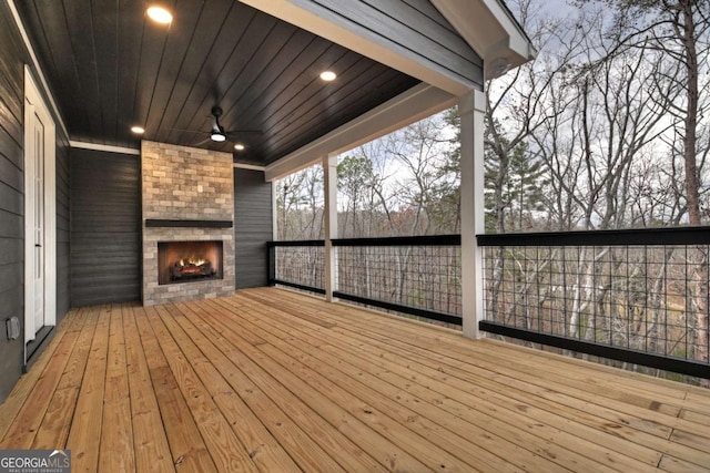 wooden terrace with a ceiling fan and an outdoor brick fireplace