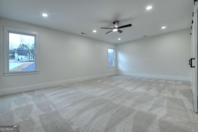 unfurnished room with visible vents, light colored carpet, baseboards, and ceiling fan