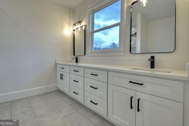 bathroom with double vanity, baseboards, tile patterned floors, and a sink