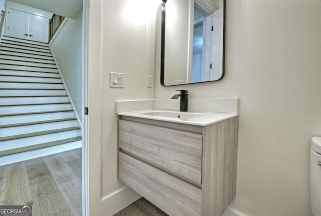 half bath featuring vanity, toilet, and wood finished floors