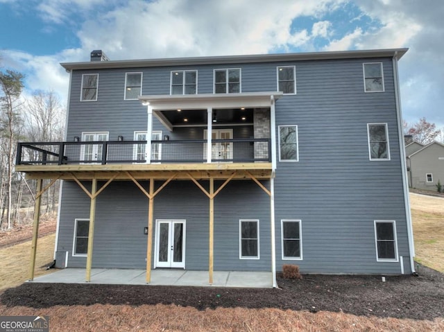 back of house with a deck, french doors, and a patio